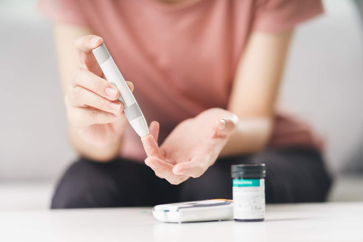 Asian woman pricking her finger to check blood sugar