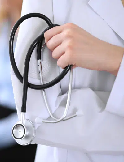 Closeup of a stethoscope held by a medical provider in a white coat