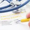 Cholesterol test results displayed with medicine and stethoscope.